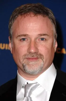 David Fincher in a suit with a goatee, blue backdrop.